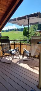 two chairs and an umbrella on a deck at Traumplatz im Allgäu in Rettenberg