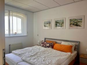 a bedroom with a bed with orange pillows and a window at De Strandloper in Julianadorp