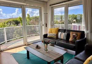 a living room with a black leather couch and large windows at De Strandloper in Julianadorp +14 photos
