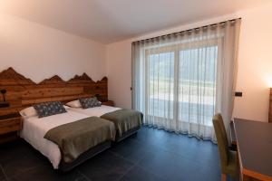 ein Schlafzimmer mit einem Bett und einem großen Fenster in der Unterkunft Malga Prefaè in Commezzadura