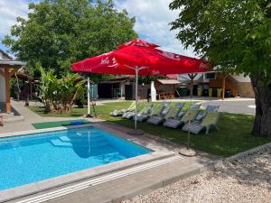 a red umbrella and chairs next to a swimming pool at Nice Big House in Balatonfenyves
