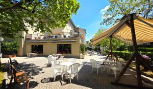 a patio with white chairs and tables and a building at Hotel Falco D'Oro by Falco D'Oro Hotels in Tolè
