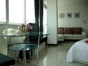 a bedroom with a bed and a glass table with flowers at Grand Residence Jomtien in Jomtien Beach