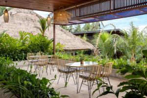 a patio with tables and chairs in a garden at Kahayana Suites Ubud in Ubud