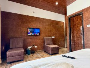 a bedroom with two chairs and a tv on the wall at Navasharada's White Sand Beach House in Udupi