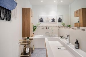 a white bathroom with a sink and a tub at EDLER WOHNRAUM Design-Loft im Graphischen Viertel 2 Schlafzimmer mit Balkon, Miele-Kaffeevollautomat, Miele-Weinkühler, Klima, Lift, Tiefgarage & WLAN 266 Mbps in Leipzig