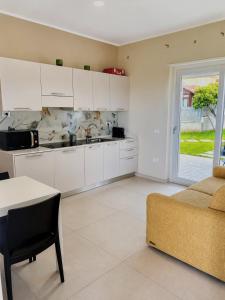 a kitchen with white cabinets and a table and a couch at SottoSopra Tropea in Tropea