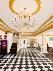a large room with a chandelier and a checkerboard floor at The Malik - An Art Deco Hotel in Birmingham