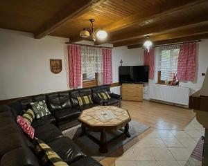 a living room with a leather couch and a coffee table at Chata Biely Potok in Oravský Biely Potok