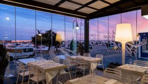 a restaurant with white tables and chairs and a large window at Hotel Roca Plana in L'Ampolla