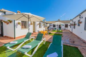 a patio with lawn chairs and an umbrella at Rivero Rural Casa Rural para Grupos y Familias en Córdoba in Posadas