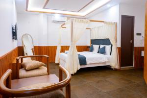 a bedroom with a canopy bed and a chair at Emmanuel Residency in Edappally
