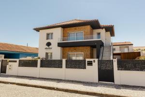 a house with a white fence at Shellter Apartments by the sea in Vieira de Leiria