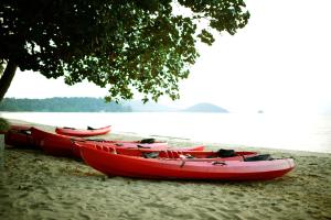 three red canoes sitting on the beach next to the water at Koh Mak Resort in Ko Mak