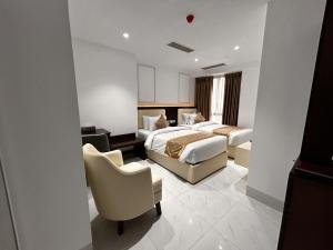 a hotel room with two beds and a chair at Royal Mark Hotel in Sylhet