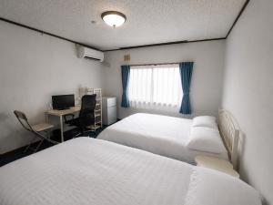 a room with two beds and a desk with a computer at Moio Homestay in Sapporo