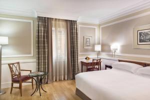 a hotel room with a bed and a table and chairs at Rome Marriott Grand Hotel Flora in Rome +107 photos