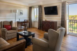 a living room with chairs and a flat screen tv at Rome Marriott Grand Hotel Flora in Rome