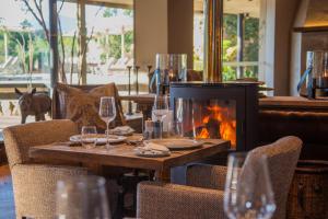 a table with glasses and a fireplace in a restaurant at Botlierskop Tented Lodge in Reebok