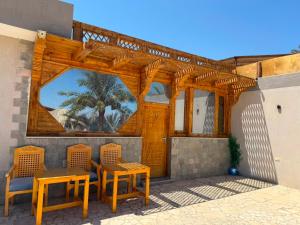 a patio with two tables and chairs and a wooden pergola at Bonanza beach camp in Nuweiba
