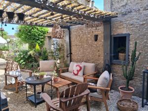 a patio with a couch and chairs under a pergola at Le Clos de l'Aiguillon in Hérouvillette