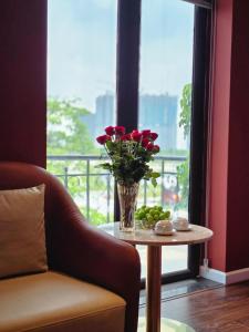 a vase of flowers on a table in front of a window at Sky Love Hotel - Trâu Qùy in Thạch Cầu