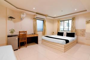 a bedroom with a bed and a desk in it at Townhouse Deshapriya Park Kolkata Formerly DK Inn in Kolkata