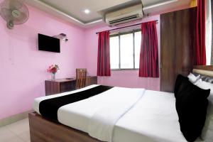 a bedroom with a large white bed with red curtains at Townhouse Deshapriya Park Kolkata Formerly DK Inn in Kolkata +34 photos
