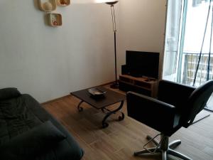a living room with a couch and a table and a television at Maison T3 - Hypercentre historique - WIFI in Villefranche-de-Rouergue