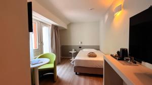 a bedroom with a bed and a desk with a television at Alchimia WellResort in Comano Terme