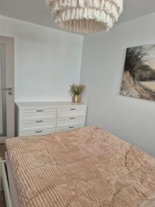 a bedroom with a bed and a chandelier at Apartament HARMONY in Koszalin