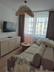a living room with a couch and a flat screen tv at Apartament HARMONY in Koszalin