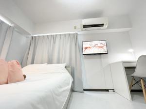 a bedroom with a bed and a desk and a tv at Kameari 1111 - 11F Newly Renovated High Floor City View 2min to Mall 5min to Station Disney Access in Tokyo +18 photos