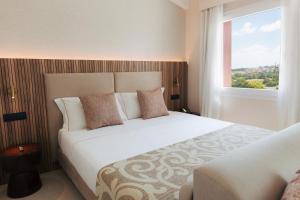 a bedroom with a large white bed with a window at PALAZZO RUBINO Aparthotel in Olbia +31 photos