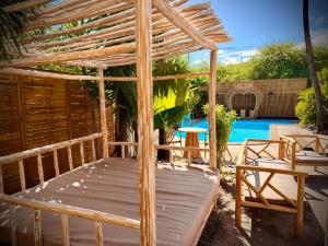 a bed with a wooden canopy next to a pool at Le Vacoa in La Saline les Bains