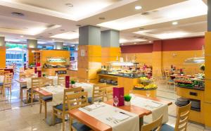 a restaurant with tables and chairs and a kitchen at SOL by Meliá Port Cambrils in Cambrils