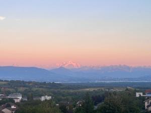 a view of a city and mountains at sunset at Cozy apartment with exceptional view in Gex +3 photos