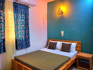 a bedroom with a bed with a blue wall at Maison fleurie Ouidah in Ouidah