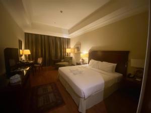 a hotel room with a white bed and a chair at Assala Hotel in Faisalabad