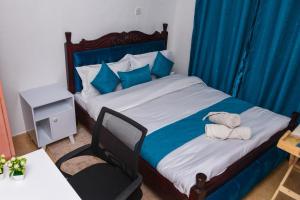 a bedroom with a bed with blue curtains and a chair at SJ Homes II in Eldoret
