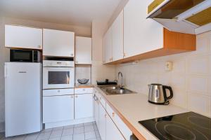 a white kitchen with white cabinets and a sink at Le Delezir - Wifi - Balcon - Plage in Saint-Nazaire