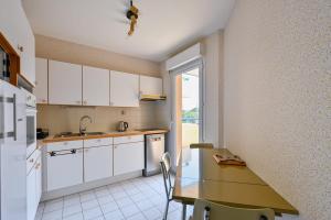 a kitchen with white cabinets and a table and a window at Le Delezir - Wifi - Balcon - Plage in Saint-Nazaire