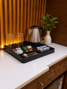 a tray with a tea kettle and cups on a counter at Comfort Sure in Amritsar