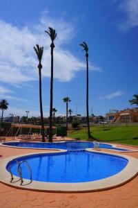 a large swimming pool with palm trees in the background at Apartamento luminoso in Mazarrón +13 photos