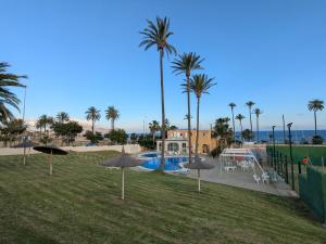 a park with umbrellas and a playground with palm trees at Apartamento luminoso in Mazarrón