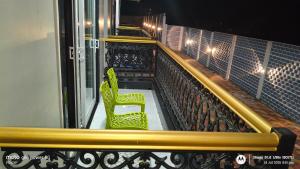 two green chairs sitting on a balcony at night at Asusss International in New Digha