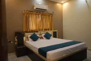 a bedroom with a bed with blue pillows at Hotel RK Royale in Patna