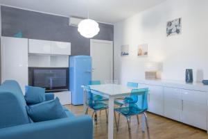 La cuisine est équipée d'une table, de chaises et d'un réfrigérateur bleu. dans l'établissement Nila Apartment, à Porto Azzurro