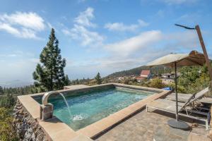 a swimming pool with an umbrella and a chair and an umbrella at El cazador 2 in Granadilla de Abona