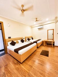 two beds in a room with wooden floors at Hotel Param INN in Gwalior